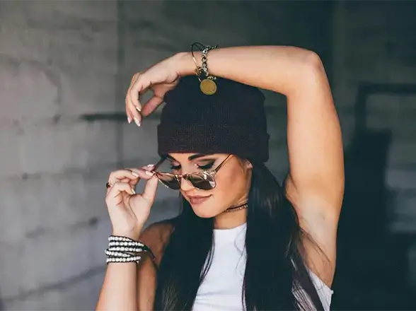 Modelo usando acessórios da marca, como pulseiras, brincos, colar e óculos de sol.